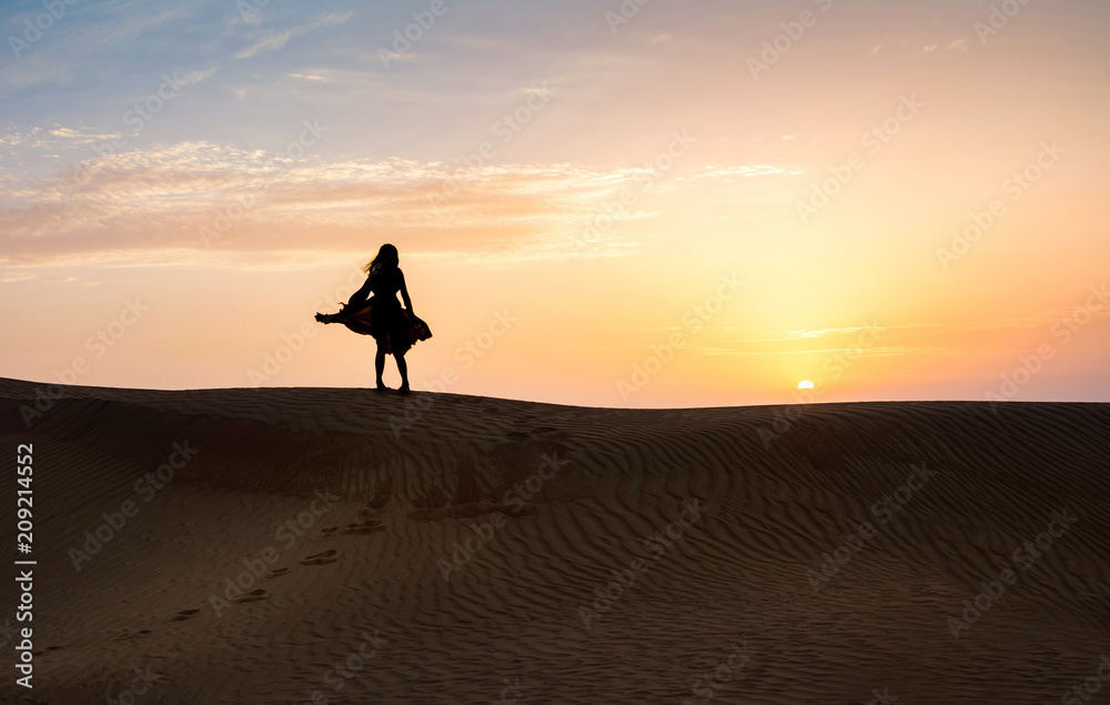 Wall mural woman in the desert with sunset view