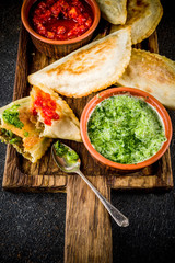 Latin American, mexican, chilean food. Traditional baked pastry empanadas with beef meat, two spicy sauces, dark rusty background copy space