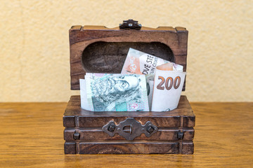 Czech koruna banknotes stuffed in a vintage wooden box. Concept of personal reserves kept in cash at home and collecting for retirement