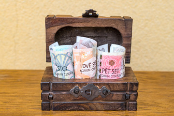 Czech koruna banknotes rolled up in a vintage wooden box. Concept of personal reserves kept in cash at home and collecting for retirement