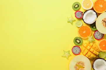 Exotic fruits on pastel yellow background - papaya, mango, pineapple, banana, carambola, dragon fruit, kiwi, lemon, orange, melon, coconut, lime. Top view.