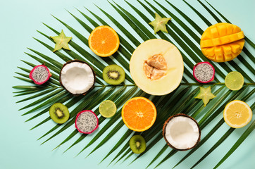 Fototapety  Exotic fruits and tropical palm leaves on pastel turquoise background - papaya, mango, pineapple, banana, carambola, dragon fruit, kiwi, lemon, orange, melon, coconut, lime. Top view.