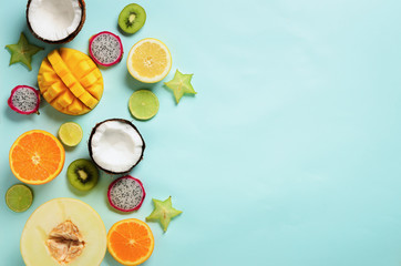 Exotic fruits on pastel blue background - papaya, mango, pineapple, banana, carambola, dragon fruit, kiwi, lemon, orange, melon, coconut, lime. Top view.
