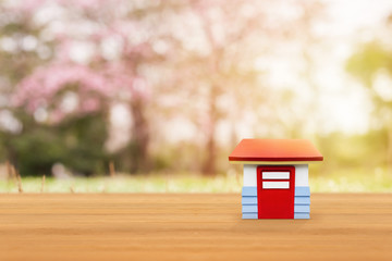 House model on wooden table up over blurred nature background. Investment and saving concept