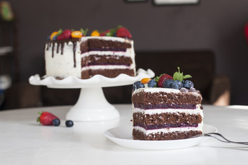 Festive chocolate cake with berry jelly, creamcheese and chocolate stains in home interior.