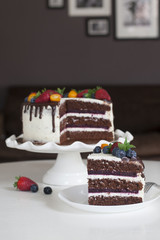 Festive chocolate cake with berry jelly, creamcheese and chocolate stains in home interior.