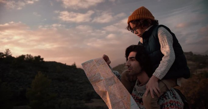 Young father and son hikers reading map on mountains