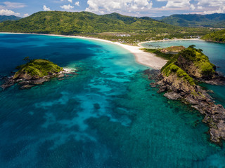 Aerial drone view of twin tropical beaches surrounded by coral reef and a clear ocean