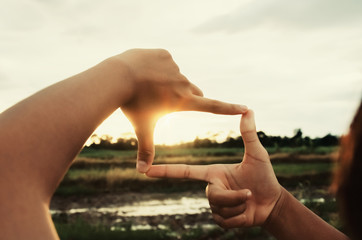 hand framing distant over sunset