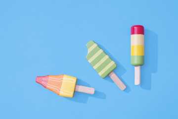 Ice cream popsicles lollipops on pastel blue background for summer.  Wooden ice cream lolly toys