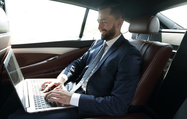 Businessman working with laptop sitting in car