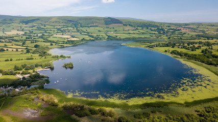 Aerial drone view of a beautiful lake surrounded by rural farmland (Llangorse Lake, Wales)