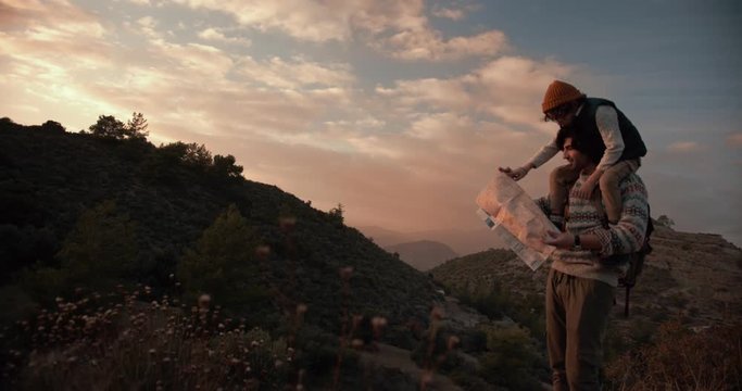 Young father and son hikers reading map and planning route