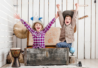 two little laughing children with hands up sitting in big old chest