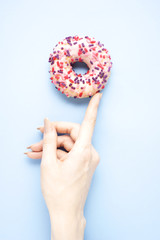 Have a snack / Creative concept photo of hand holding donut on blue background.