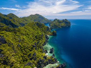 Fototapeta na wymiar Aerial drone view of spectacular tropical scenery with towering cliffs, jungle and pristine sandy beaches