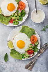 green spinach crepes with fried eggs, smoked salmon and vegetables for breakfast