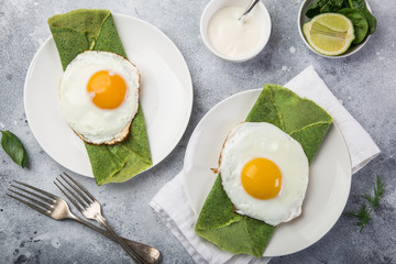 green spinach crepes with fried eggs for breakfast