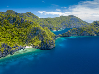 Aerial drone view of spectacular limestone cliffs, jungle, sandy beaches surrounded by coral reef