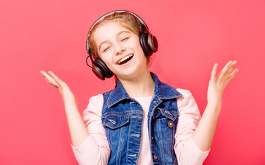 Cute young teen girl enjoying listening to music in wireless headset over rose background