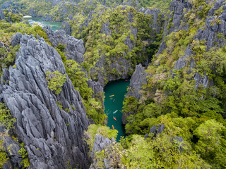 Aerial drone view of kayaks inside a beautiful shallow tropical lagoon surrounded by jagged cliffs and jungle (Small Lagoon, El Nido)