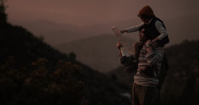 Young father and son hiking and reading map on mountains