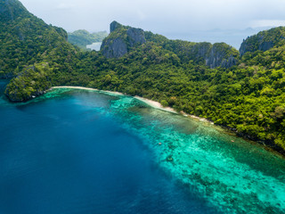 Aerial drone view of an unihabited tropical island with rugged mountains, jungle and sandy beaches
