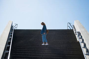 side view of woman standing on steps with blue sky on background in copenhagen, denmark