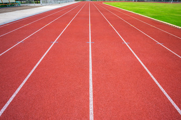 White lines of stadium and texture of running racetrack red rubber racetracks in outdoor stadium are 8 track and green grass field,empty athletics stadium with track,football field, soccer field.