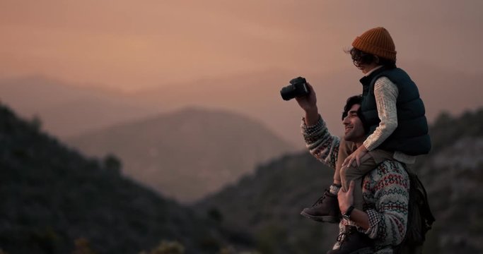 Young father and son taking photos on mountain hiking adventure