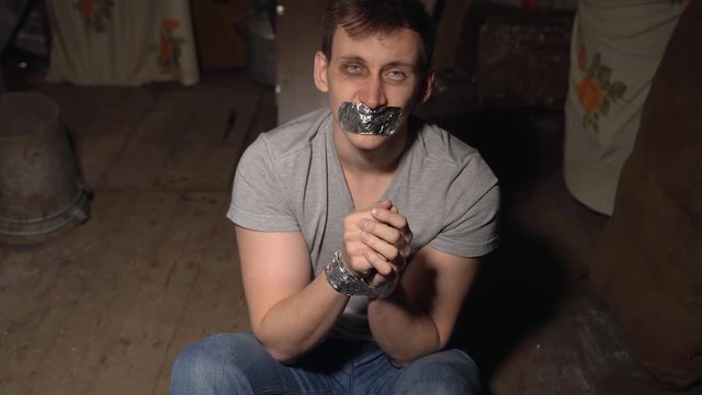 Hostage. A young man in a dark room with a black eye.