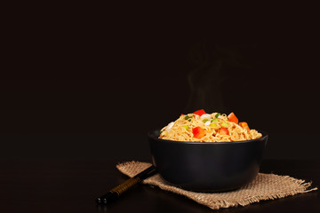 Instant noodles in the bowl with tomato and onion on wooden table