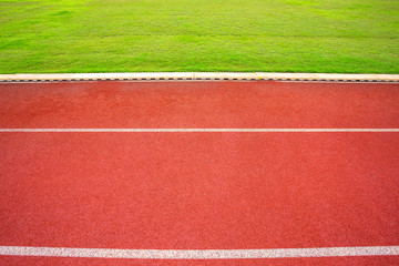 Fototapeta premium White lines of stadium and texture of running racetrack red rubber racetracks in outdoor stadium are 8 track and green grass field,empty athletics stadium with track,football field, soccer field.