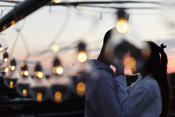 Boy and girl hug each other tender standing on the rooftop in the rays of evening lights