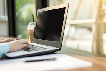 Fototapeta premium Close-up of business female working with laptop make a note document and smartphone in coffee shop like the background.