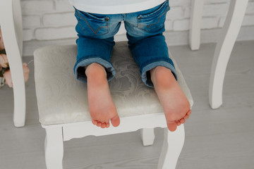 Children's legs. Feet of the baby. on the chair.