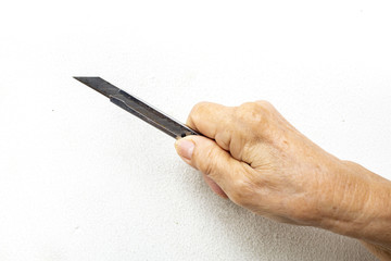 Senior woman's hand holding a cutter knife on white background