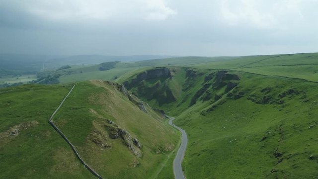 Long winding road between two scenic  Hills on a sunny day with dark clouds in background 4