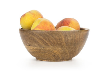 Yellow peaches in a wooden bowl isolated on white background.