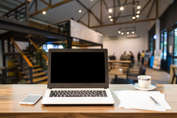 Mockup image of laptop with blank black screen on wooden table of In the coffee shop.