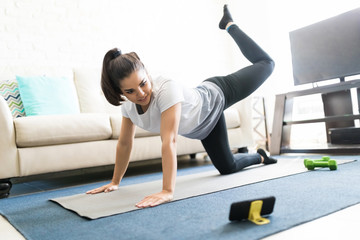 Active woman working out at home with online class