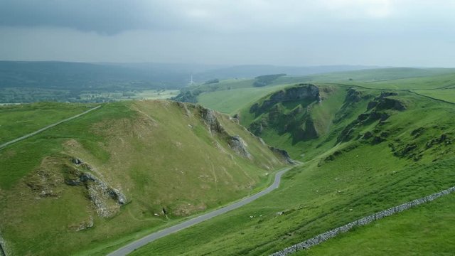 Long winding road between two scenic  Hills on a sunny day with dark clouds in background 2