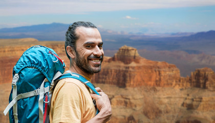 adventure, travel, tourism, hike and people concept - close up of smiling man with backpack over...