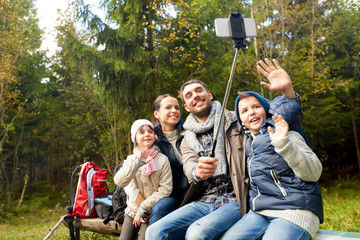 adventure, travel, tourism and people concept - happy family hiking and taking selfie by smartphone in woods