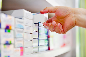Main de pharmacien de plan rapproché tenant la boîte de médecine dans la pharmacie de pharmacie.