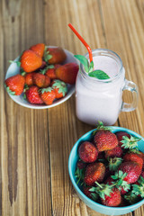Strawberry yogurt or smoothie on a wooden background with ripe berries