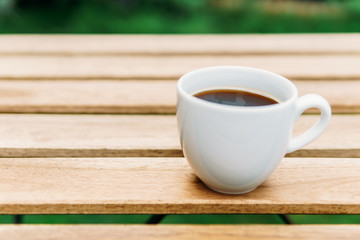 White Coffee Cup On Wooden Table In Green Garden