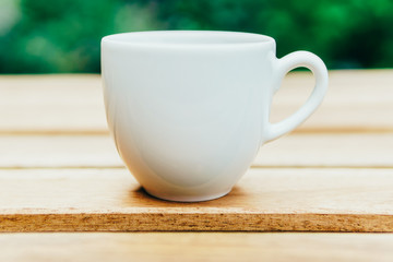 White Coffee Cup On Wooden Table In Green Garden