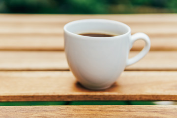 White Coffee Cup On Wooden Table In Green Garden