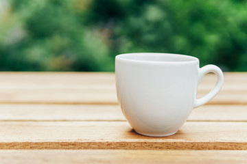 White Coffee Cup On Wooden Table In Green Garden